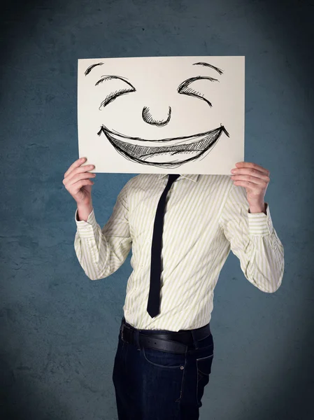 Businessman holding a paper with smiley face in front of his hea — Stock Photo, Image