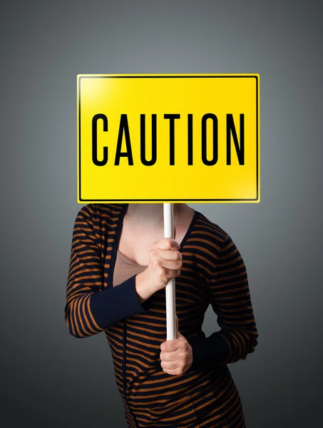 Young woman holding a caution sign — Stock Photo, Image