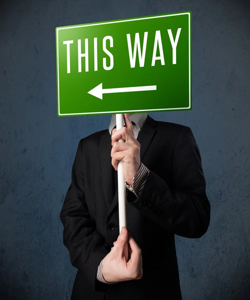 Businessman holding a direction sign — Stock Photo, Image