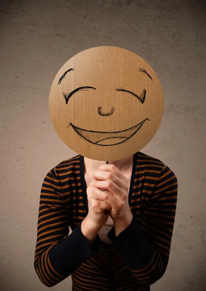 Young woman holding a smiley face board — Stock Photo, Image