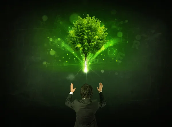 Businessman gesturing in front of a glowing tree — Stock Photo, Image