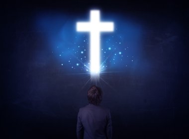 Businessman in front of a glowing cross