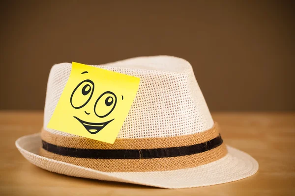 Nota post-it con la cara sonriente pegada en el sombrero — Foto de Stock