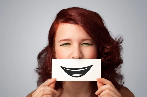 Happy pretty woman holding card with funny smiley — Stock Photo, Image