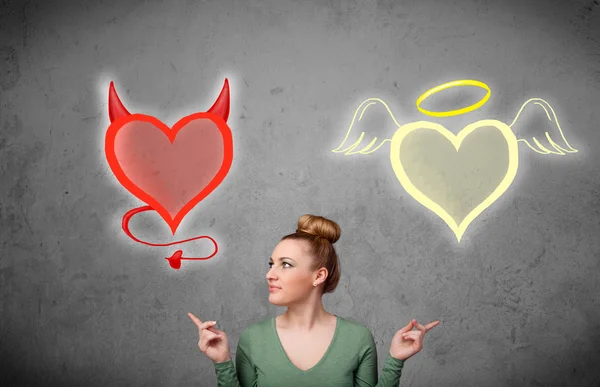 Femme debout entre l'ange et les cœurs du diable — Photo