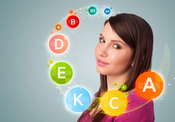 Pretty young girl with colorful vitamin icons and symbols — Stock Photo, Image