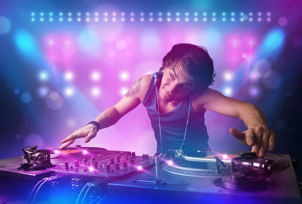 Disco jockey mezcla de música en los tocadiscos en el escenario con luces y —  Fotos de Stock