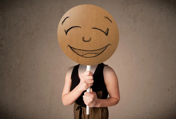 Mujer joven sosteniendo una carita sonriente — Foto de Stock