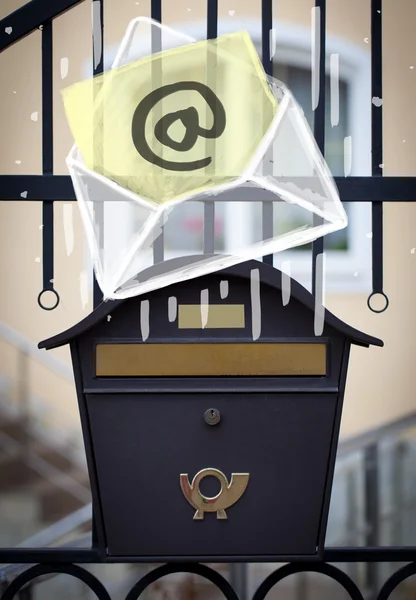 Envelope with email sign dropping into mailbox — Stock Photo, Image