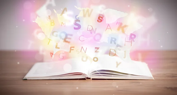Open book with glowing letters on concrete background — Stock Photo, Image