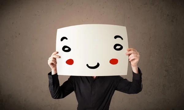 Businessman holding a cardboard with a smiley face on it — Stock Photo, Image