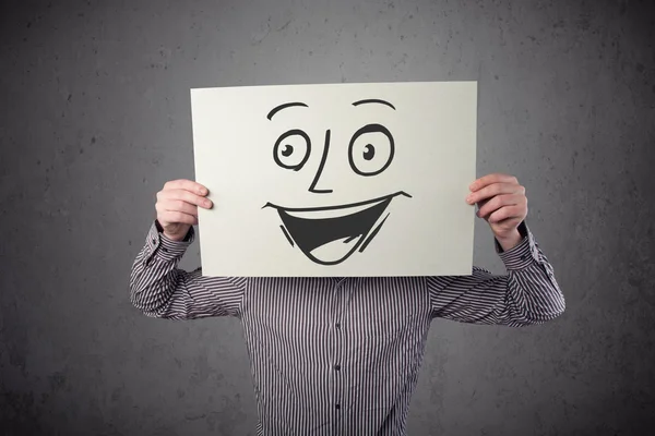 Empresário segurando um papelão com rosto sorridente na frente — Fotografia de Stock