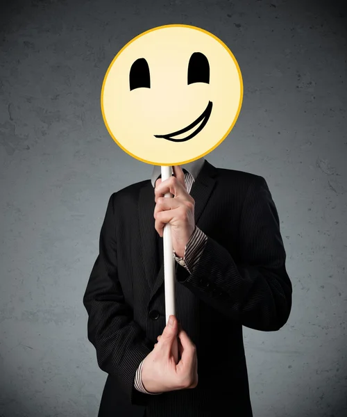 Empresário segurando um emoticon rosto sorridente — Fotografia de Stock