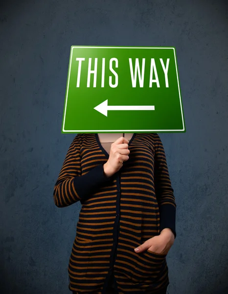 Young woman holding a direction sign — Stock Photo, Image