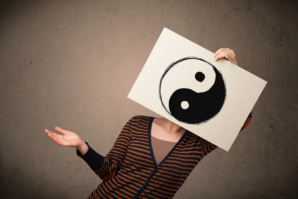 Donna che tiene un foglio con uno yin-yang davanti alla testa — Foto Stock