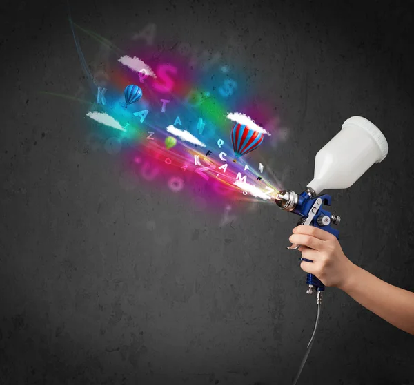 Worker with airbrush and colorful abstract clouds and balloons — Stock Photo, Image