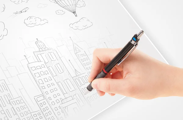 A person drawing sketch of a city with balloons and clouds on a — Stock Photo, Image