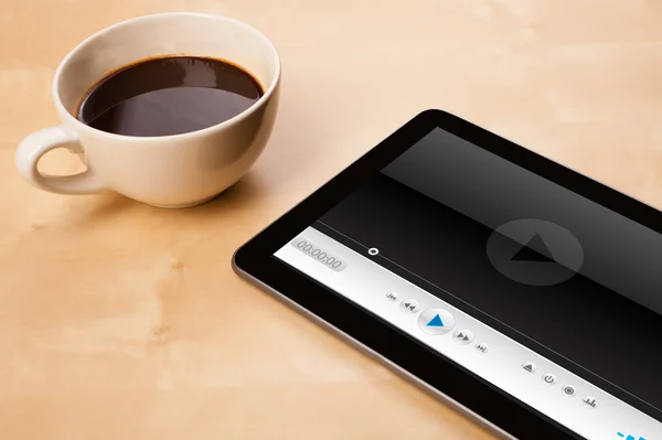 Tablet PC que muestra el reproductor multimedia en la pantalla con una taza de café en —  Fotos de Stock