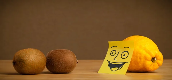 Lemon with post-it note smiling at kiwis — Stock Photo, Image