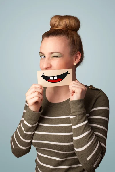 Happy pretty woman holding card with funny smiley — Stock Photo, Image