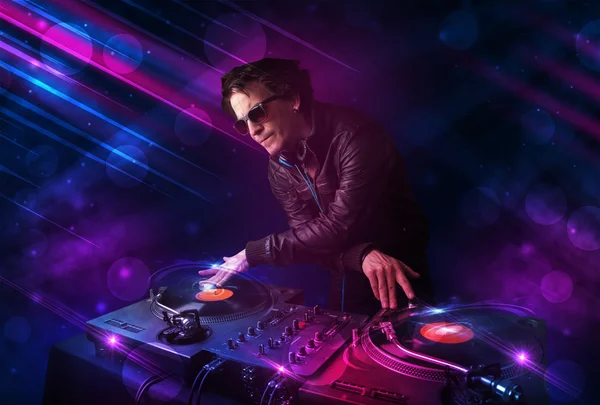 Young DJ playing on turntables with color light effects — Stock Photo, Image