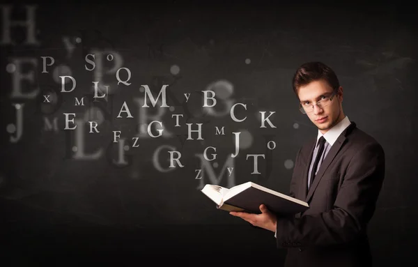 Young man reading a book with alphabet letters — Stock Photo, Image