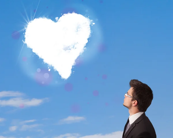 Hombre guapo mirando la nube blanca del corazón en el cielo azul — Foto de Stock