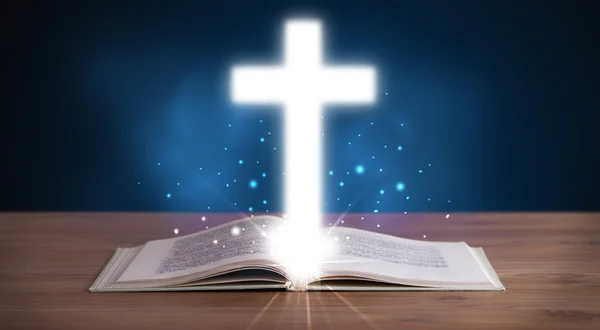 Open holy bible with glowing cross in the middle — Stock Photo, Image