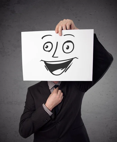 Businessman holding a cardboard with smiley face on it in front — Stock Photo, Image