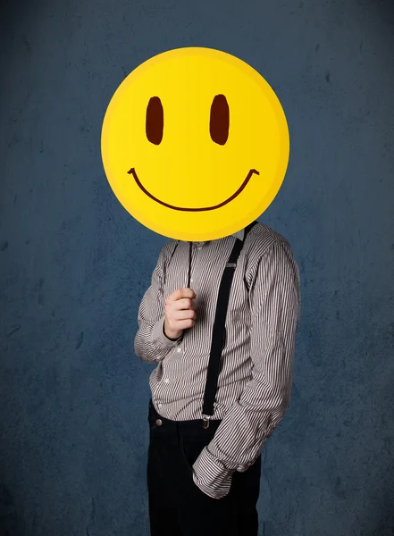 Uomo d'affari che tiene un faccina faccina sorridente — Foto Stock