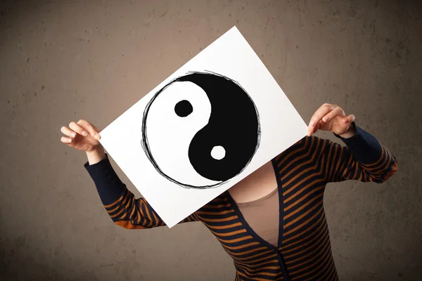 Woman holding a paper with a yin-yang on it in front of her head — Stock Photo, Image