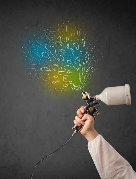 Worker with airbrush gun paints colorful lines and splashes — Stock Photo, Image