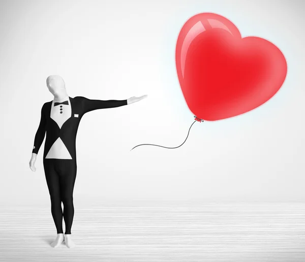 Cute guy in morpsuit body suit looking at a balloon shaped heart — Stock Photo, Image