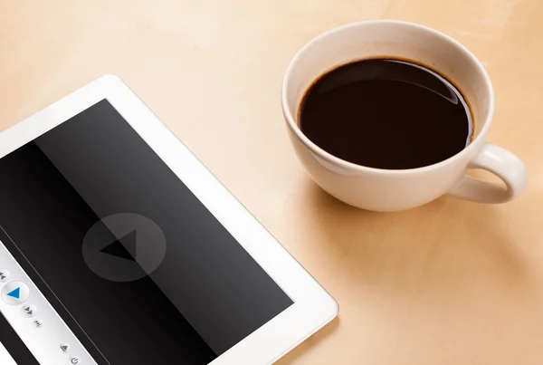 Tablet pc showing media player on screen with a cup of coffee on — Stock Photo, Image