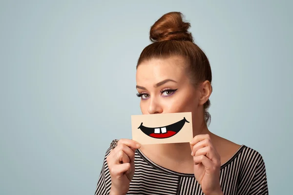 Happy pretty woman holding card with funny smiley — Stock Photo, Image