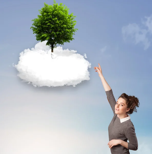 Молодая девушка указывает на зеленое дерево на вершине белого облака — стоковое фото