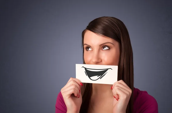 Happy cute girl holding paper with funny smiley drawing — Stock Photo, Image