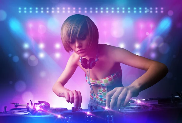 Disc jockey mixando musica sui giradischi sul palco con luci e — Foto Stock