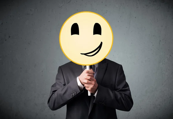 Empresário segurando um emoticon rosto sorridente — Fotografia de Stock