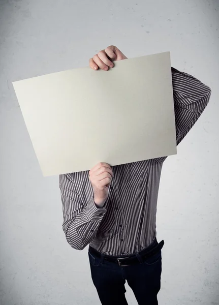 Geschäftsmann hält sich ein Papier mit Kopierplatz vor den Kopf — Stockfoto