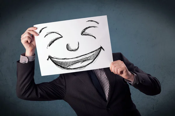 Empresário segurando um papel com rosto sorridente na frente de sua hea — Fotografia de Stock