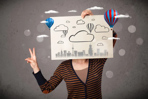 Woman holding a cardboard with cityscape in front of her head — Stock Photo, Image