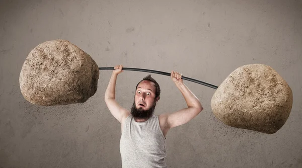 Skinny guy lifting large rock stone weights — Stock Photo, Image