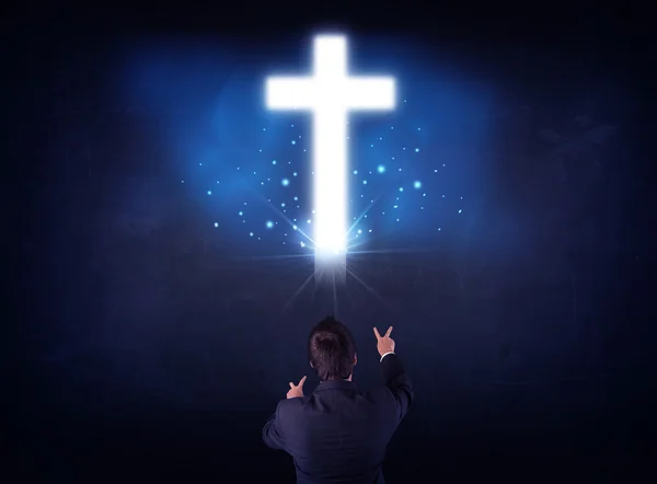 Businessman in front of a glowing cross — Stock Photo, Image