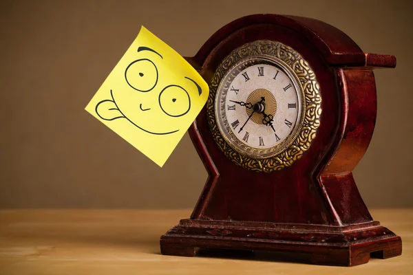 Nota post-it con la cara sonriente pegada en un reloj — Foto de Stock