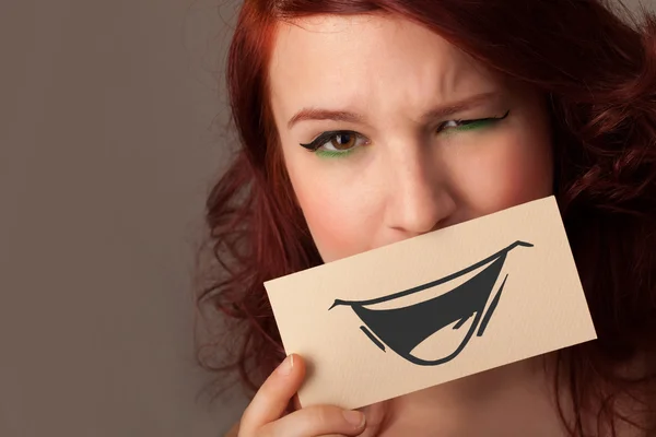 Happy cute girl holding paper with funny smiley drawing — Stock Photo, Image