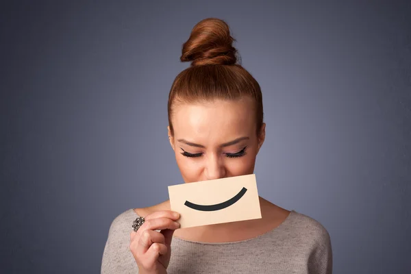 Happy pretty woman holding card with funny smiley — Stock Photo, Image