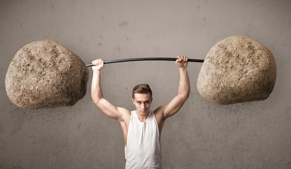 Hombre muscular levantando grandes pesos de piedra de roca —  Fotos de Stock