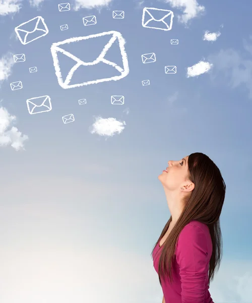 Chica joven mirando el símbolo de correo nubes en el cielo azul — Foto de Stock