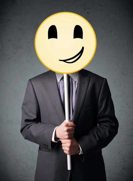 Empresário segurando um emoticon rosto sorridente — Fotografia de Stock